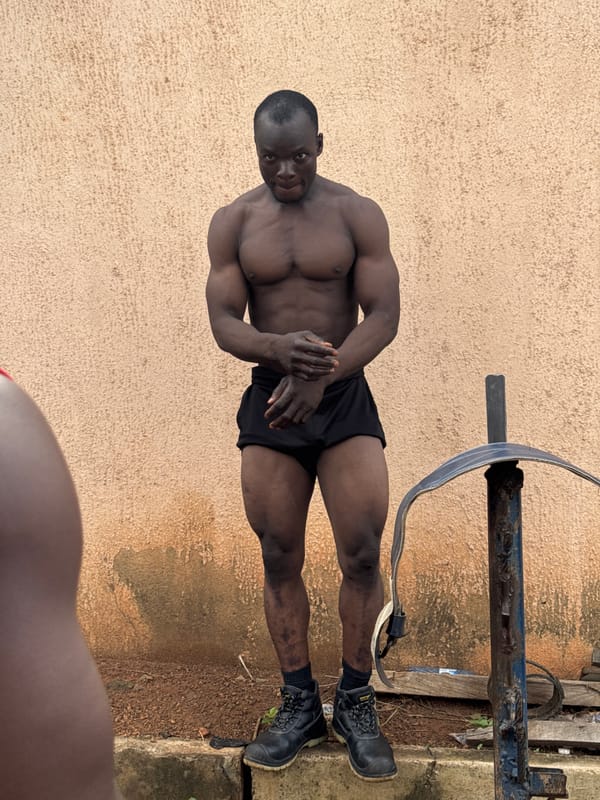 Outdoor bodybuilding session beside a rusty structure in Akwanga