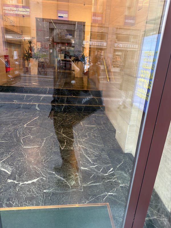 Window reflection captures Milan street scene with Italian storefronts