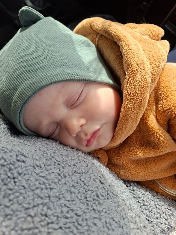Baby sleeps peacefully in green hat in Karsha, Russia