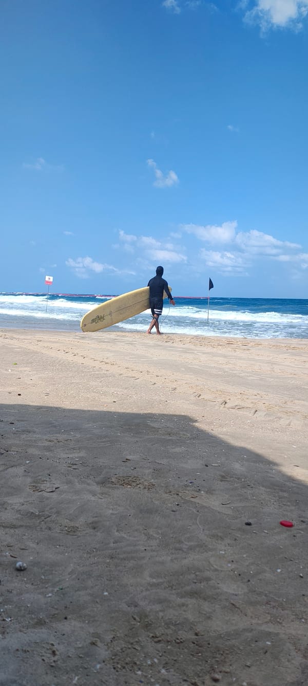 Surfers and a beach tractor on a choppy shoreline