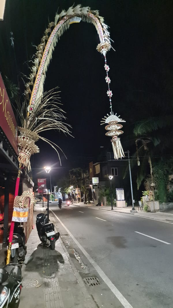 Denpasar streets at night, with Balinese offerings on a parked car