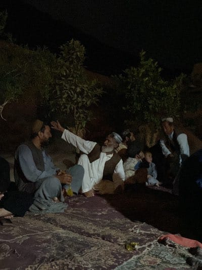 Men gather on rug for evening social meeting in Dehkheshk
