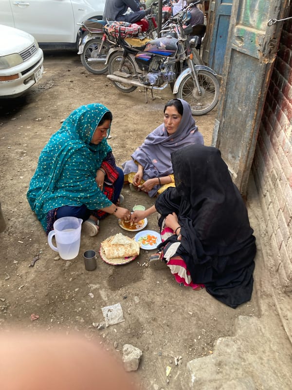 Three women share outdoor meal in Quetta alleyway