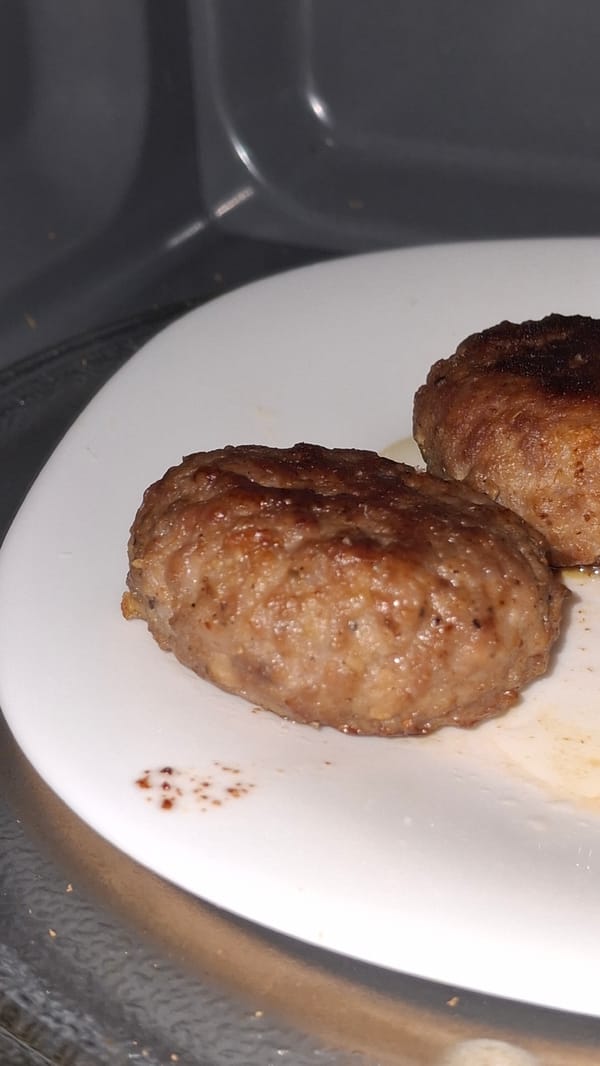 Two meatballs documented on white plate at unknown location