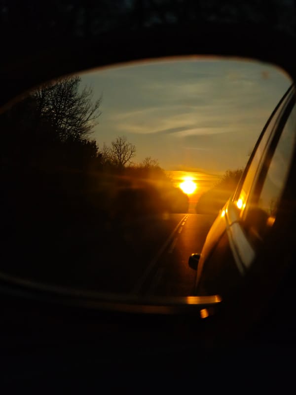 Driver captures sunset road view in car mirror