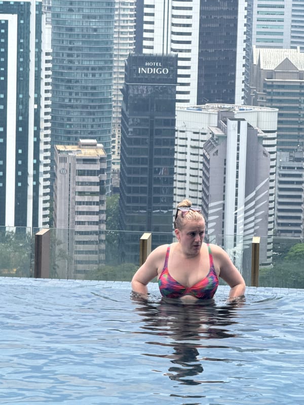 Woman enjoys early morning pool time above Kuala Lumpur skyline