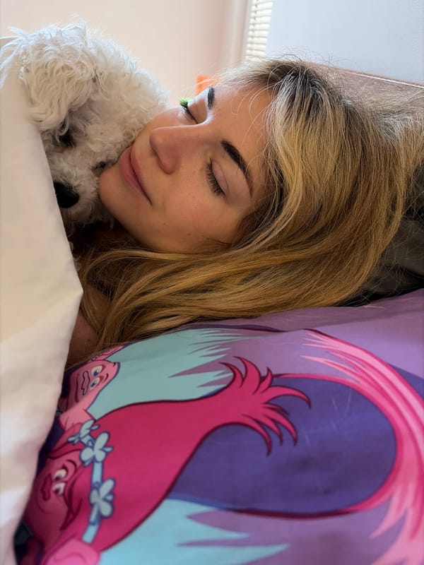 Woman rests peacefully in bed with white Bichon Frise