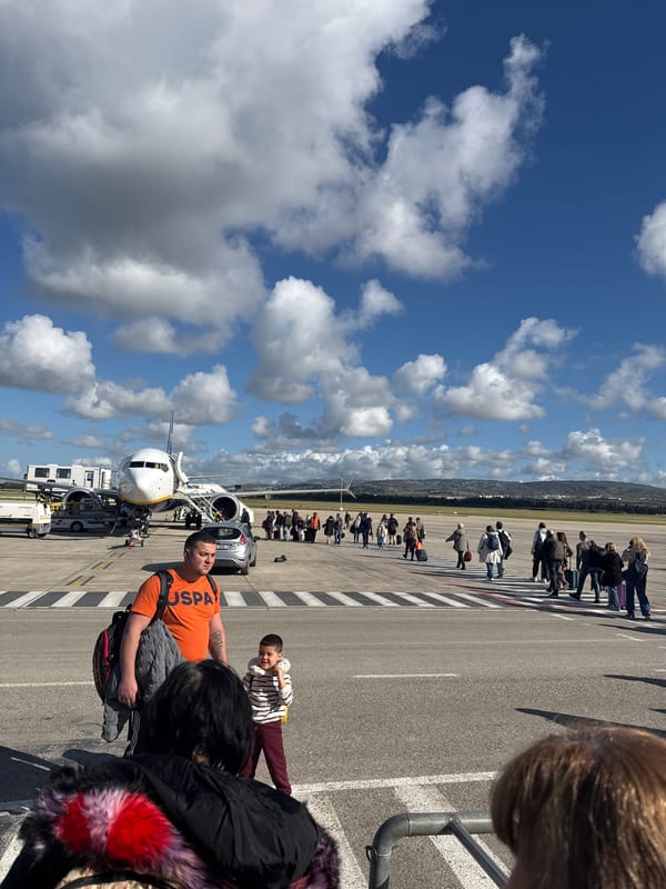 Passengers queue on sunny airport tarmac for aircraft boarding