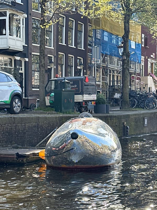 Canal boat tour navigates Amsterdam waterways on sunny afternoon