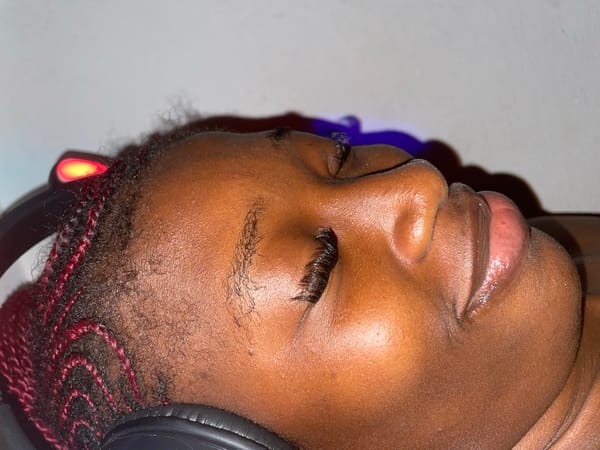 Person with braids listens to headphones under colored lights