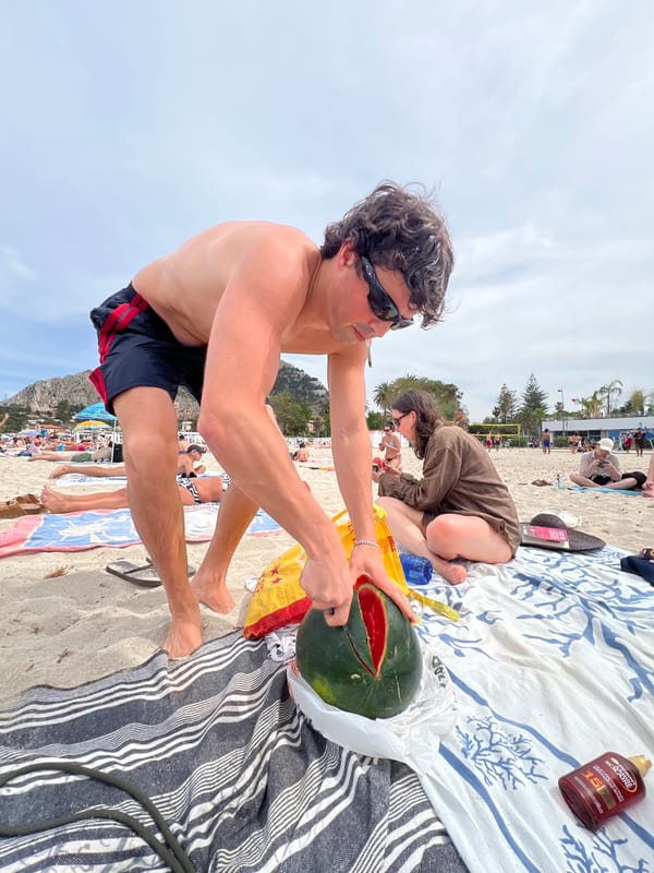 Man cuts watermelon on busy Palermo beach