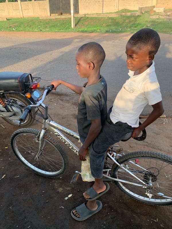 Two boys share bicycle moment in Kabba, Nigeria