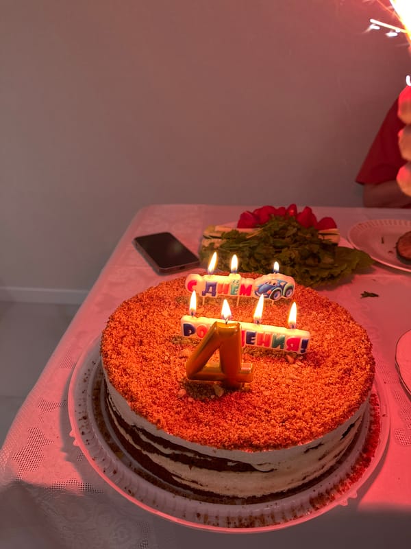 Birthday cake with Cyrillic candles on a lace tablecloth