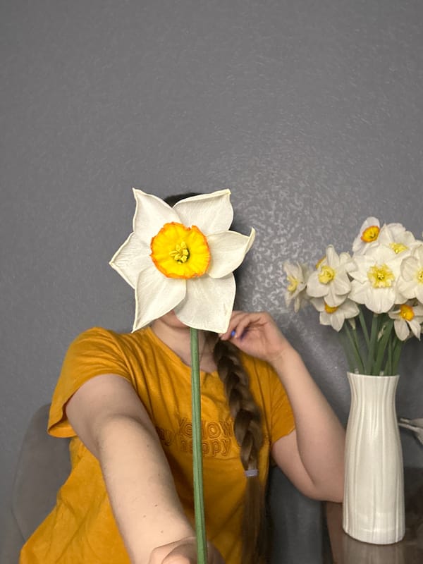 Woman in yellow shirt documents spring flowers at home