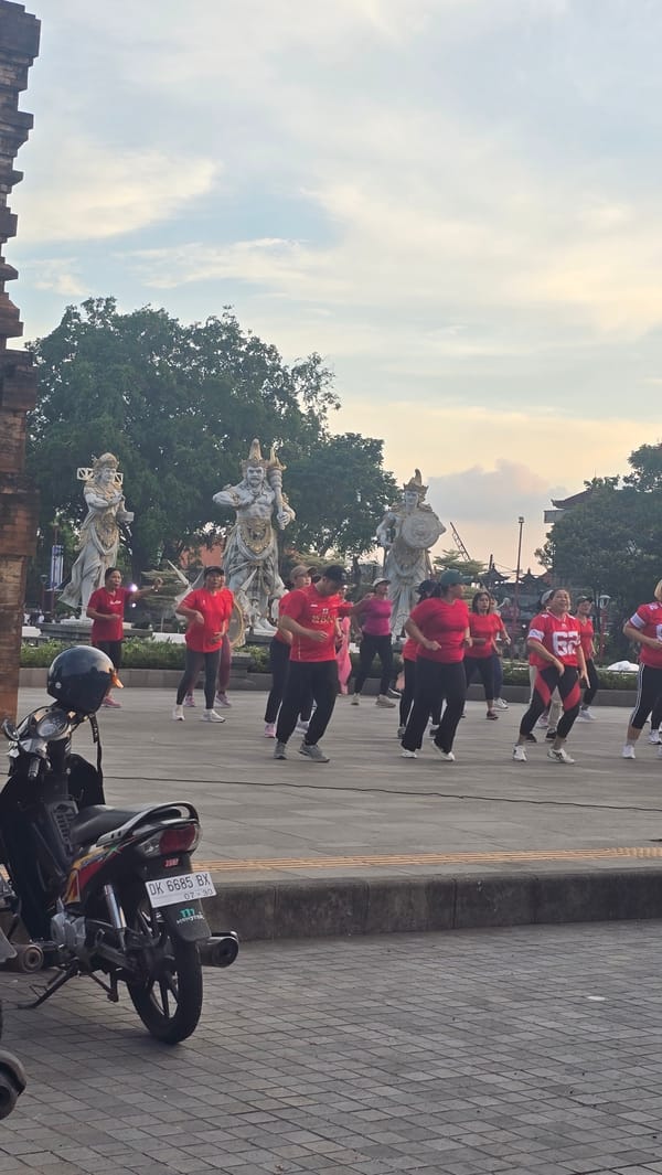Women's exercise group gathers near traditional statues in Gianyar