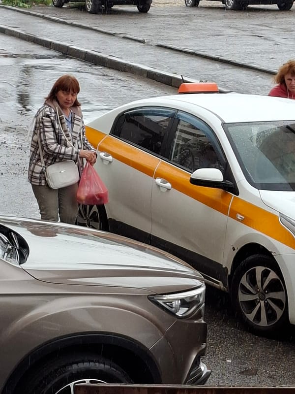 Rainy urban street scene with taxis, pedestrians, and shopping bags