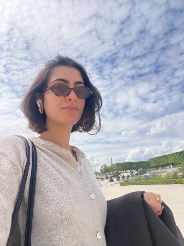 Woman takes selfies in Parisian park amid green chairs