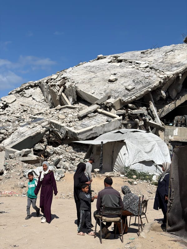 Woman tends to child amid Gaza rubble and shelters