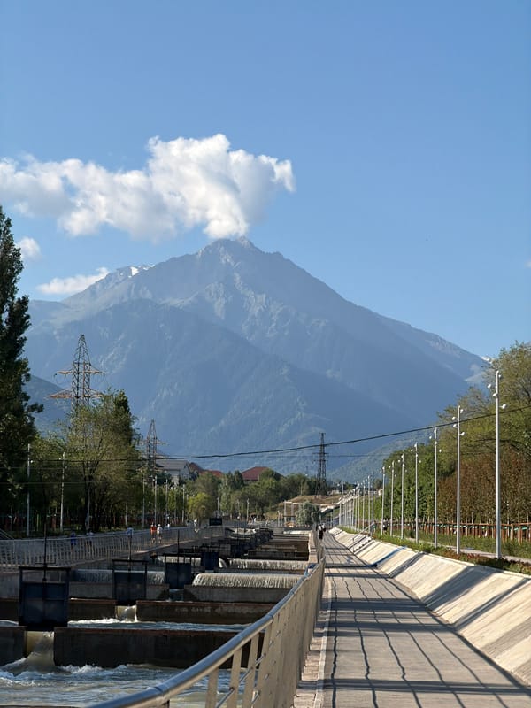 Snow-capped peaks and a paved path on Almaty's mountain edge