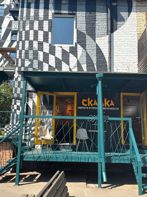 Checkered mural wraps a brick cafe storefront with teal metalwork