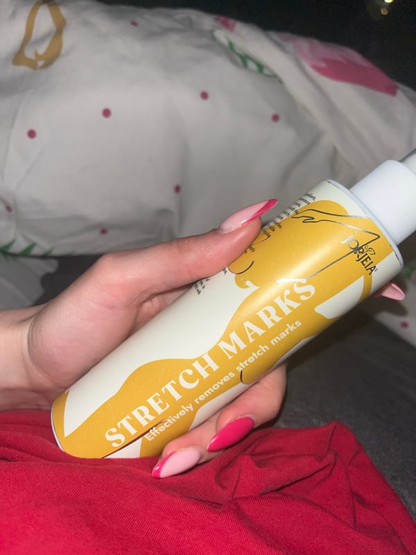 Woman displays stretch mark cream in bedroom in Pernik