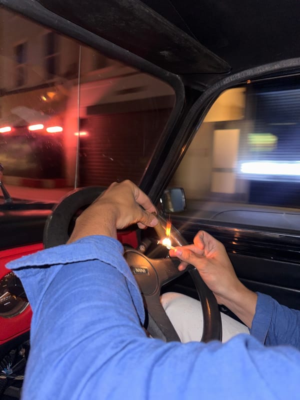 Person lights cigarette in car near illuminated London Eye