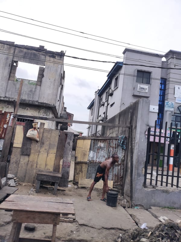 Man carries bucket near concrete structure in Alaiyabiagba, Nigeria