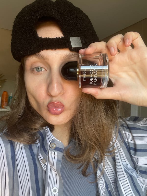 Person poses with luxury perfume bottle in rural Russia