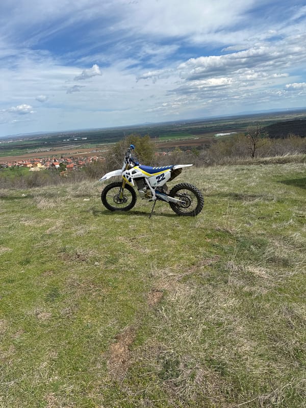 Dirt bike rider takes break on hillside near tower