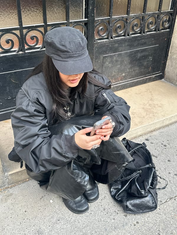 Person in military cap sits by ornate gate in Paris