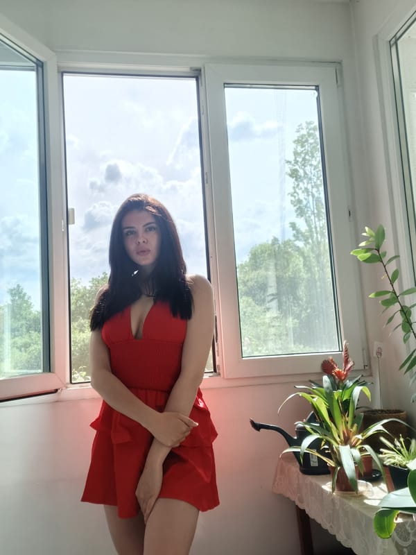 Woman in red dress sits on Sofia windowsill