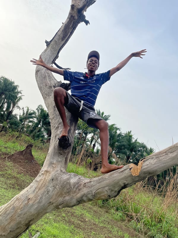 Young man plays on fallen tree in rural Nigeria