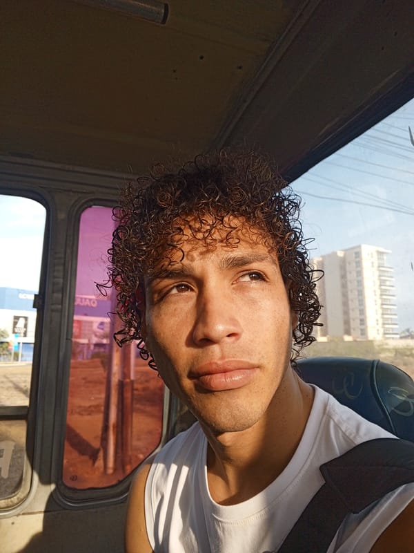 Young man rides bus, gazes at building in Porlamar