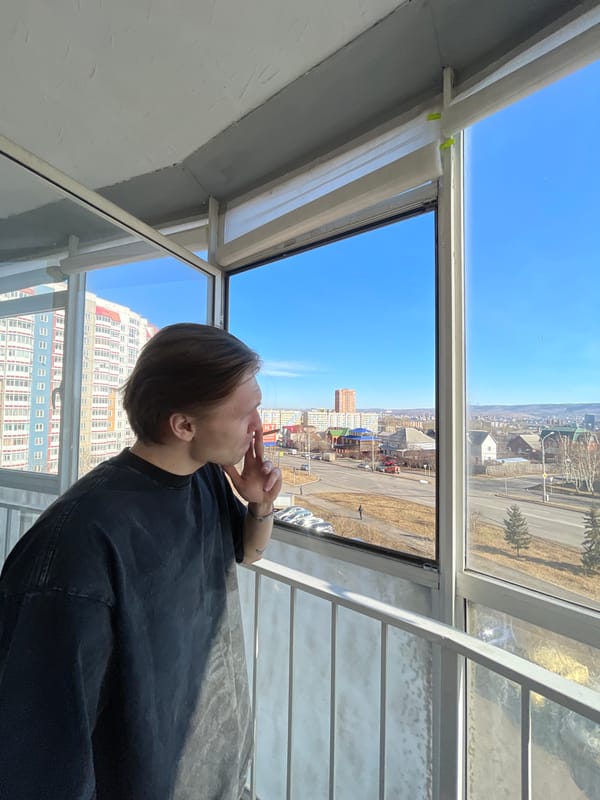 Person gazes at cityscape from window in Krasnoyarsk