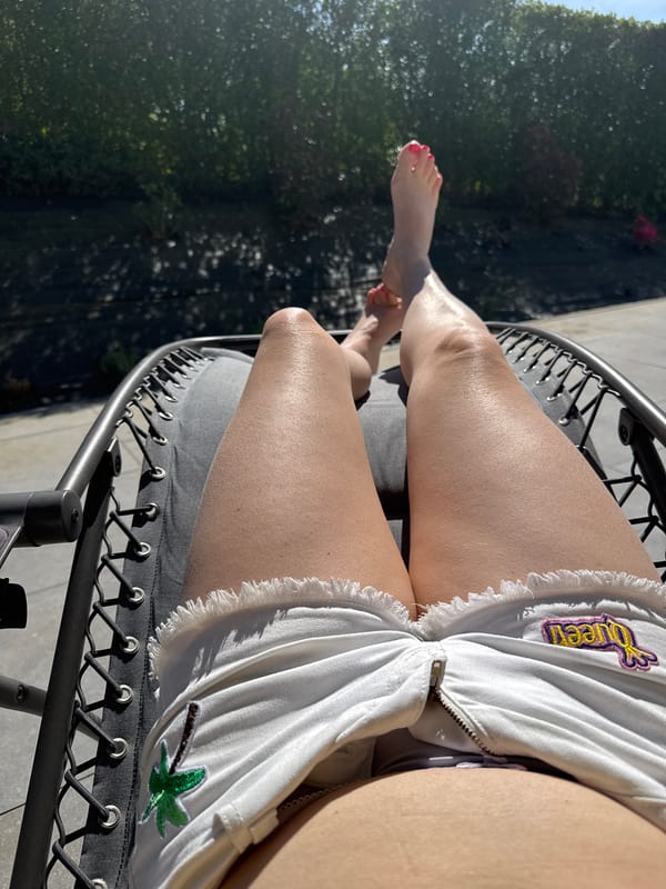 Person in decorated shorts sits outdoors in Belgian town