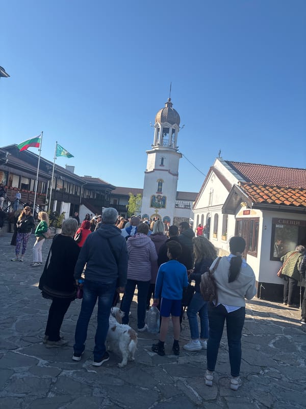 People gather around white bell tower in Pomorie square