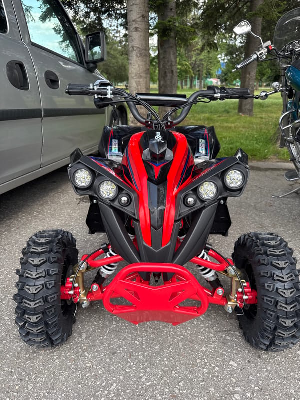 Boy rides red ATV on grass and asphalt surfaces
