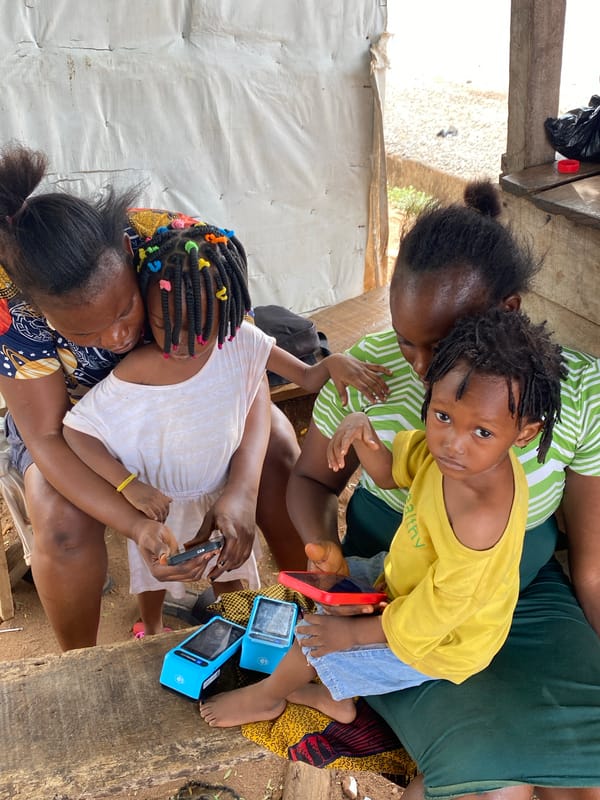 Two women, two children gather on bench in Adankolo