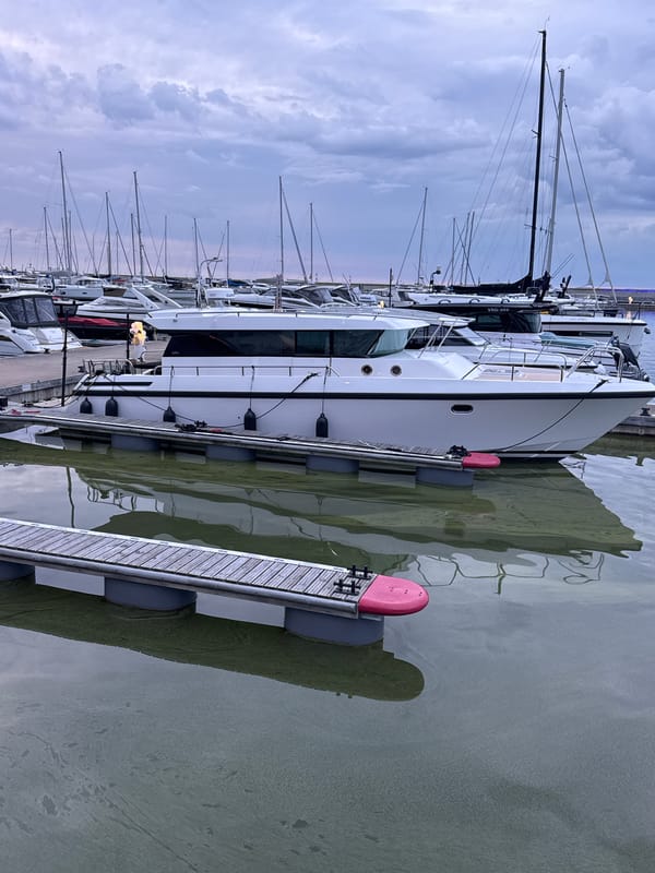 Tallinn marina at dusk, boats docked, waterfront path busy
