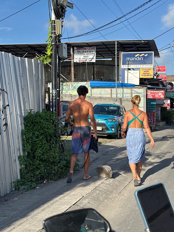 Scooters, surfers, and foot traffic on a North Kuta street