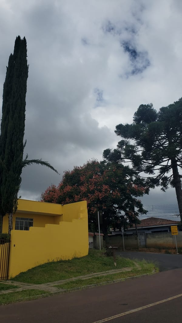 Yellow gated building observed in Curitiba under cloudy skies
