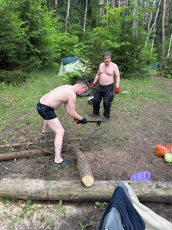 Men camping, preparing firewood at Belarus lakeside location