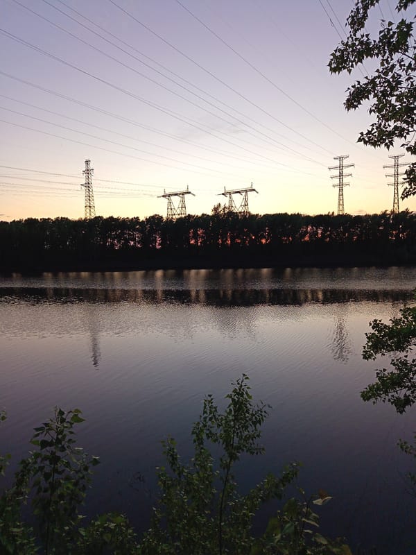 Peaceful waterside scene with power lines near Chaikovsky