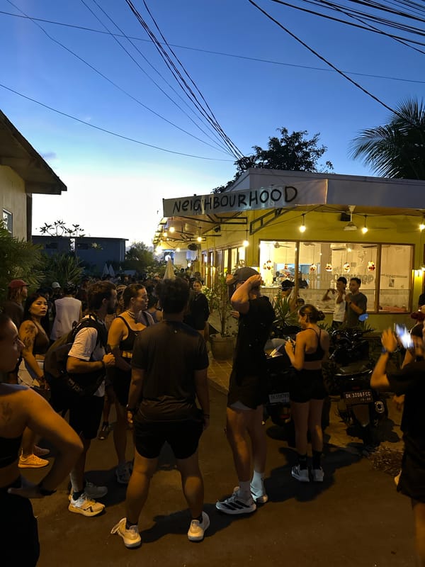 Crowd gathers at dusk outside Cemagi neighborhood building