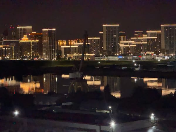 Tyumen's illuminated skyline reflects across the waterfront at night