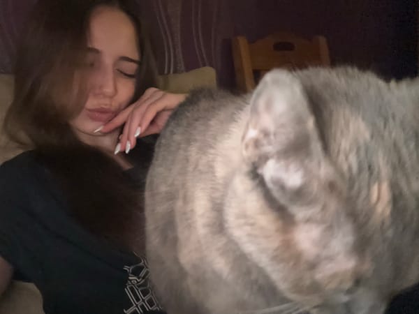 Woman and cat rest together on bed in Pernik
