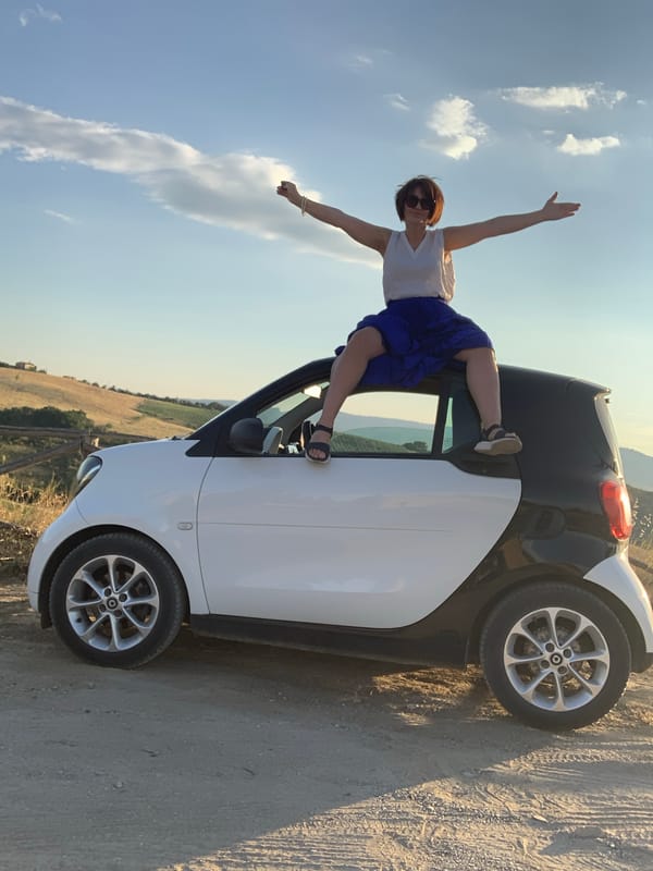 Arms out on a Smart car rooftop in San Quirico d'Orcia