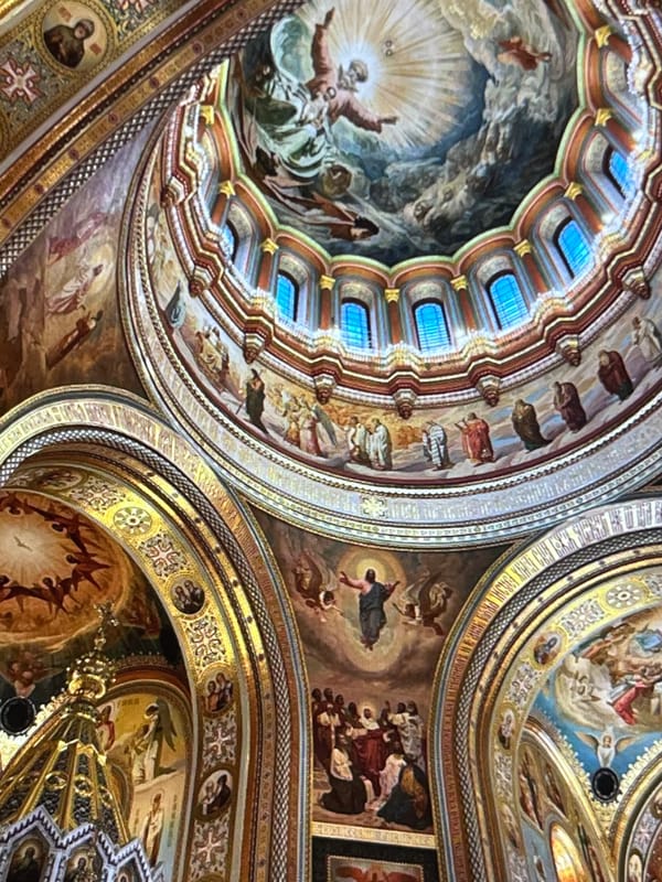 Ornate church interior: frescoed ceiling and glowing candelabra