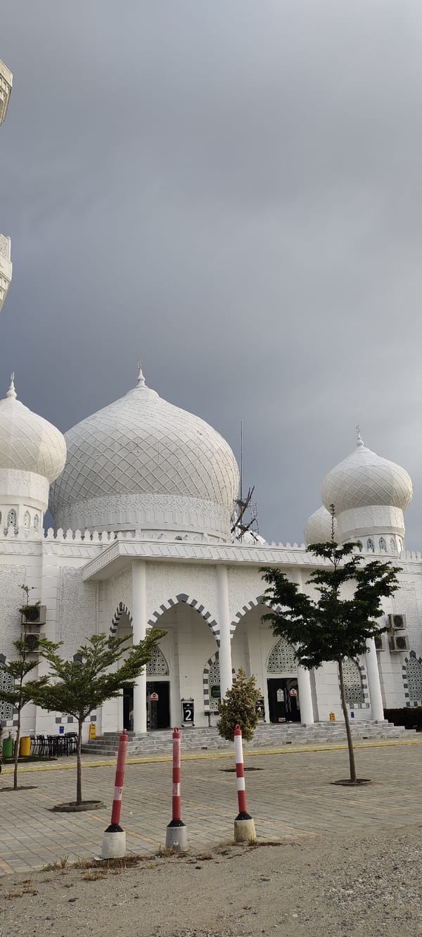 White mosque, bougainvillea, and hazy skies on a cloudy morning