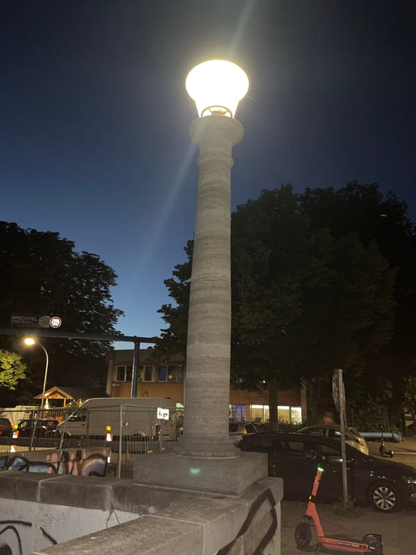 Ornate lamppost lights up a Berlin street at dusk